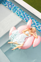 Woman on pink flamingo float in light blue pool