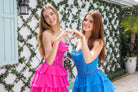 Two girls in pink and teal dresses making a heart.